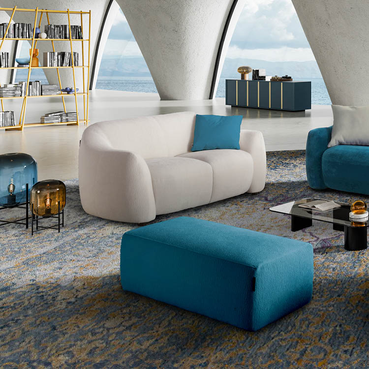 Un salon moderne avec un canap beige, un pouf bleu, une table basse en verre, une  tag re jaune remplie de livres et une grande baie vitr e donnant sur la mer.  Description g n r e par IA