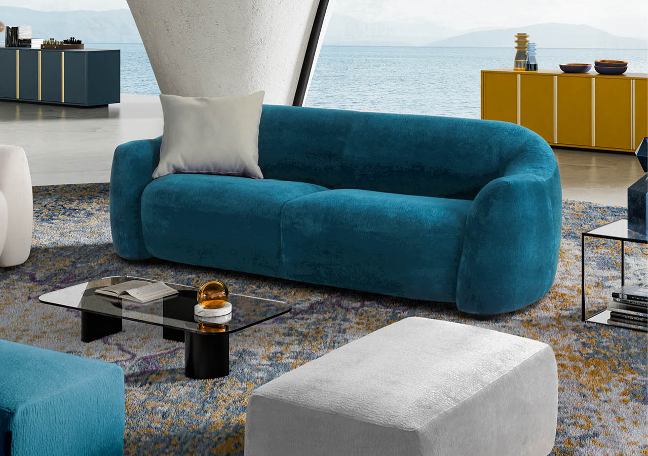 Un salon moderne avec un canap bleu turquoise arrondi, un coussin gris, une table basse en verre noir, un pouf gris et des meubles jaunes et bleus en arri re-plan avec une vue sur la mer.  Description g n r e par IA