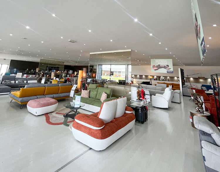 Un grand showroom lumineux pr sente plusieurs canap s modernes de diff rentes couleurs et styles dispos s sur un sol clair avec des lampes et des d corations autour. Description g n r e par IA
