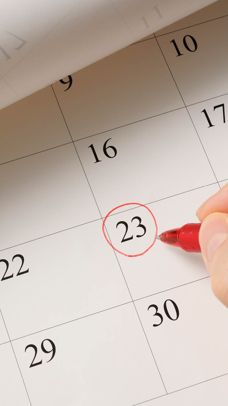 Writing a date on calendar by red pen.