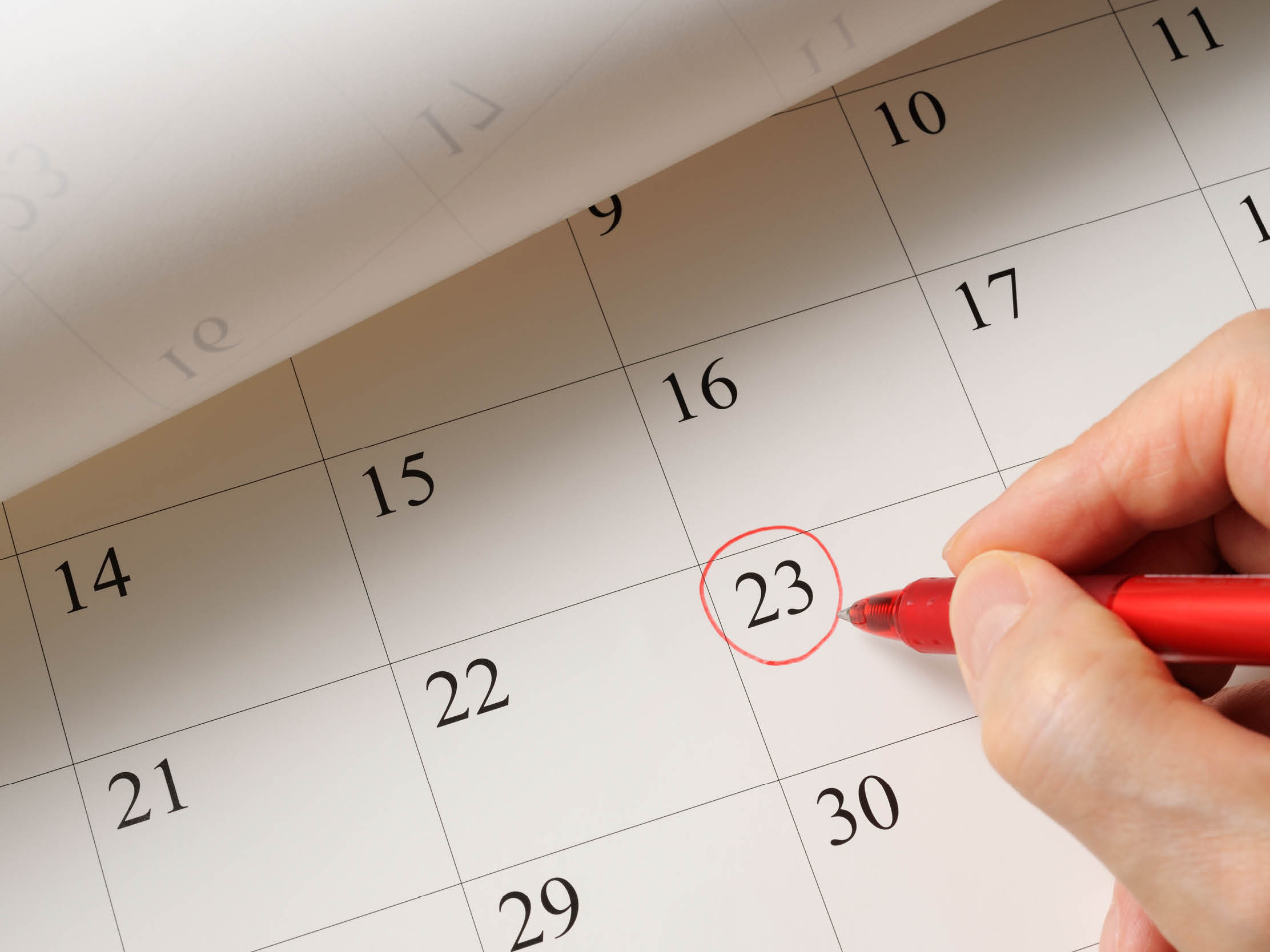 Writing a date on calendar by red pen.