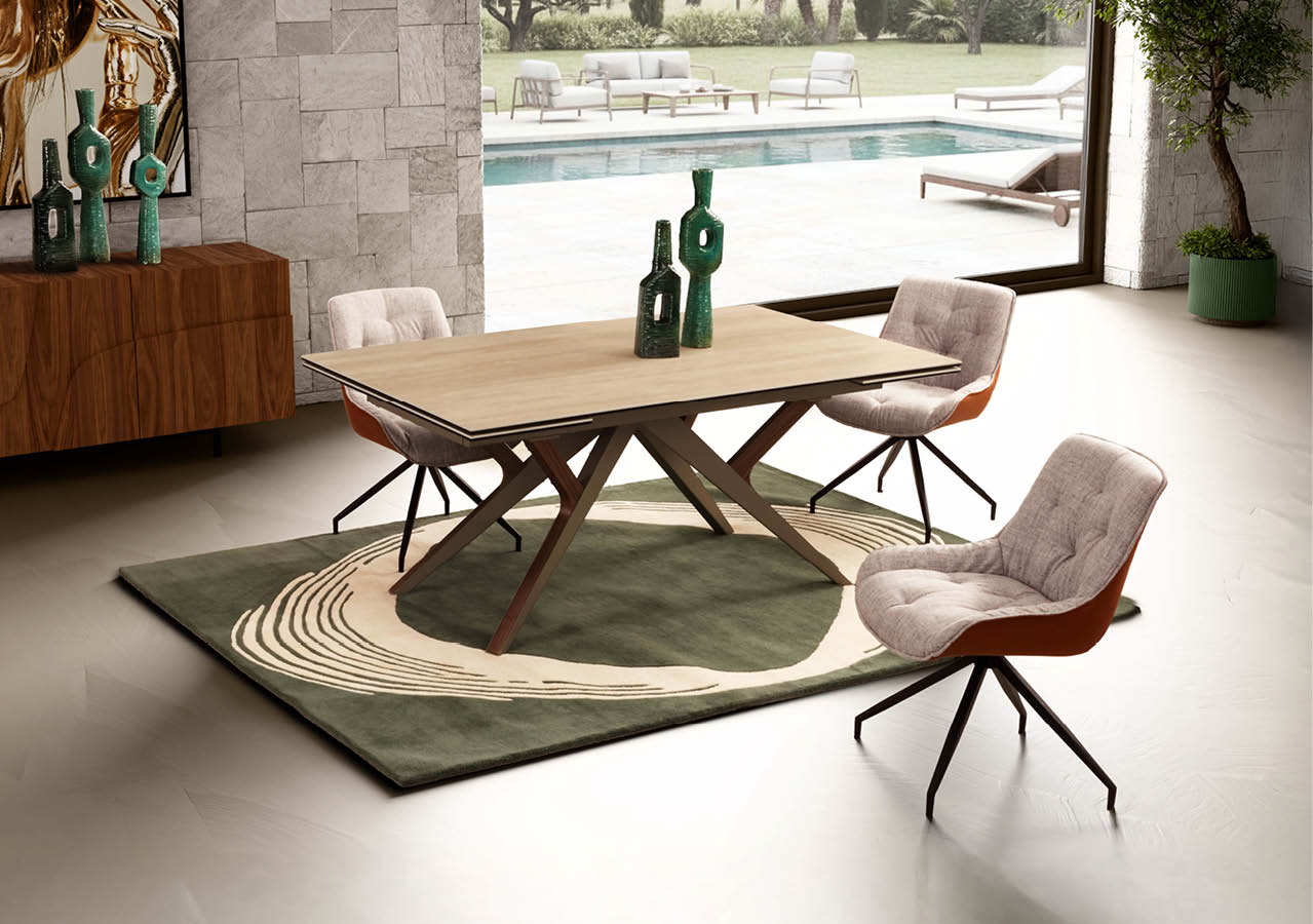 Salle  manger moderne avec une table en bois clair entour e de quatre chaises rembourr es sur un tapis vert et beige, avec une grande baie vitr e donnant sur une piscine et un jardin.  Description g n r e par IA