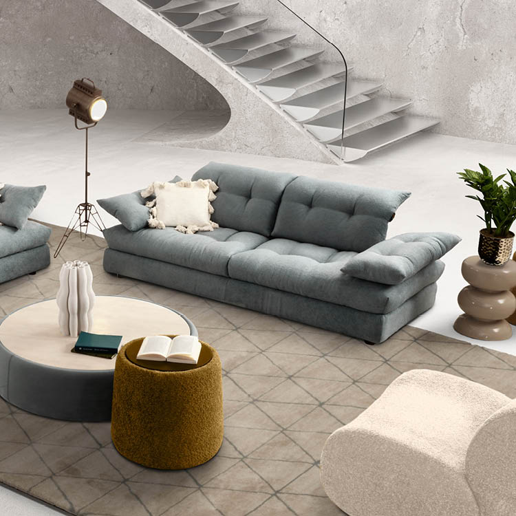 Un salon moderne avec un canap gris, un fauteuil beige, une table basse ronde avec des livres, une lampe sur pied et une plante d corative pr s d'un escalier en b ton.  Description g n r e par IA