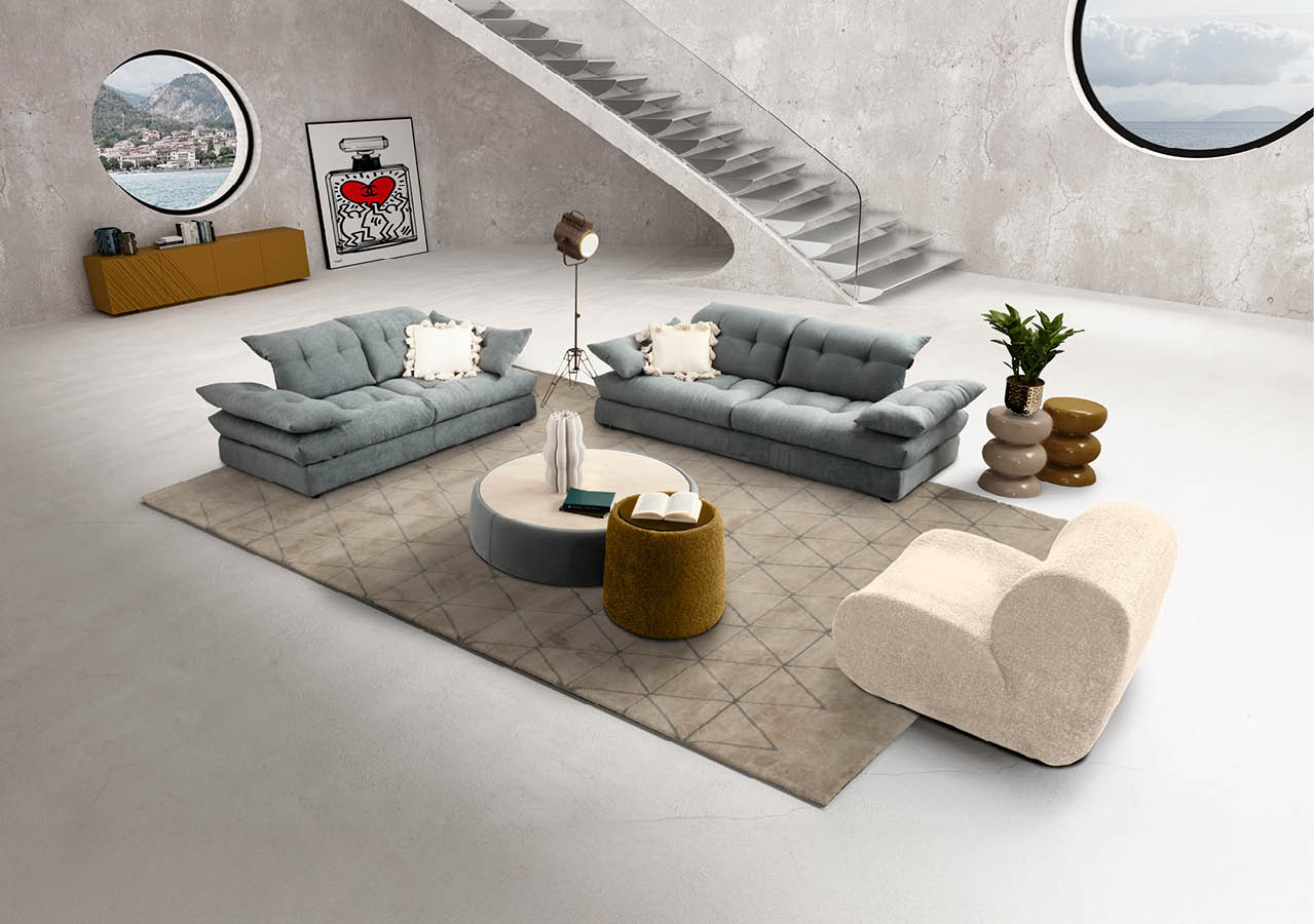Salon moderne avec deux canap s gris, un fauteuil beige, une table basse ronde, un tapis et un escalier en b ton dans un espace minimaliste avec deux fen tres rondes. Description g n r e par IA