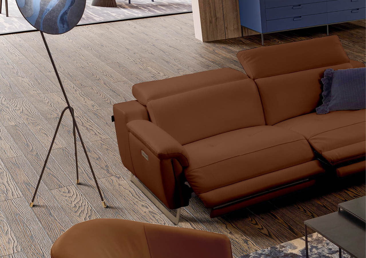 Canap en cuir marron avec un coussin bleu dans un salon au sol en bois clair et un lampadaire moderne   tr pied.  Description g n r e par IA