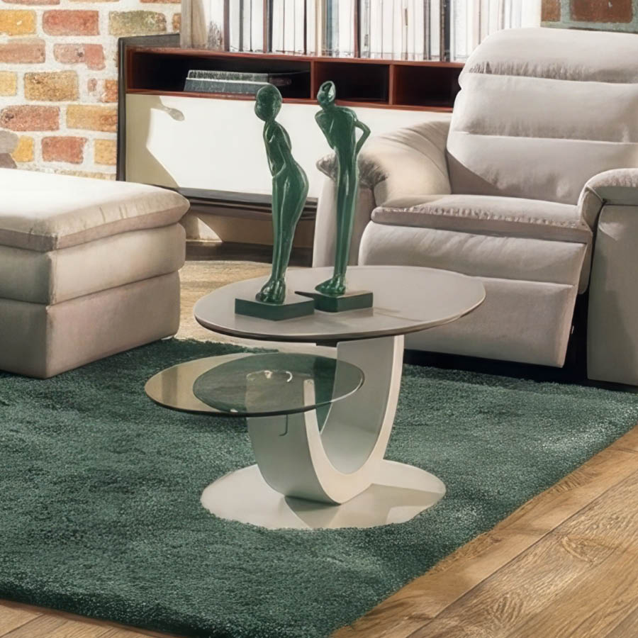 Une table basse moderne avec un plateau ovale gris et un plateau en verre en forme de demi-lune est pos e sur un tapis rouge pais avec deux petites statues rouges de personnes pench es en avant.  Description g n r e par IA