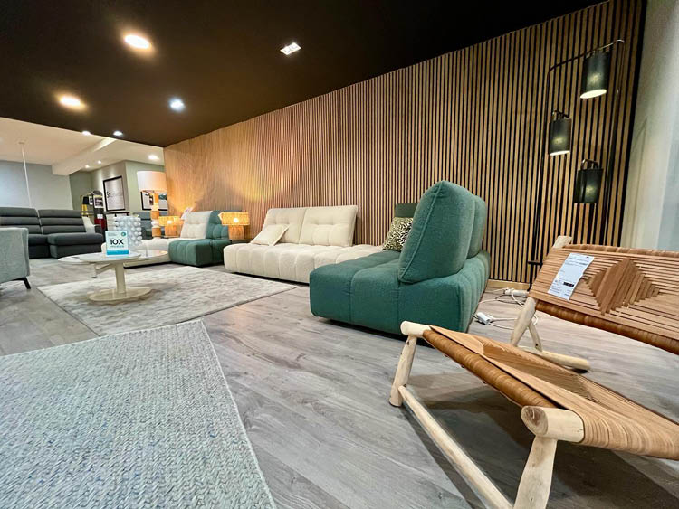 Salon moderne avec canap s et fauteuils de diff rentes couleurs dispos s autour d'une table basse sur un sol en bois clair avec un mur en bois  l'arri re-plan.  Description g n r e par IA