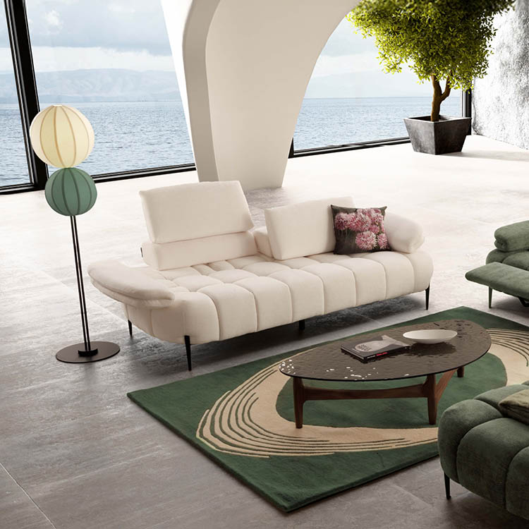 Un salon moderne avec un canap beige, un tapis vert avec un motif beige, une table basse en bois, une lampe sur pied   deux abat-jours color s et une grande fen tre donnant sur une vue sur l'eau.  Description g n r e par IA