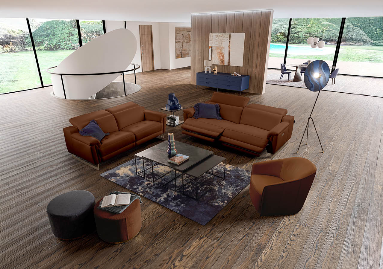 Un salon moderne avec deux canap s en cuir marron, un fauteuil assorti, une table basse noire sur un tapis, une lampe sur pied design et un escalier blanc en colima on dans un espace lumineux avec de grandes baies vitr es donnant sur un jardin. Description g n r e par IA
