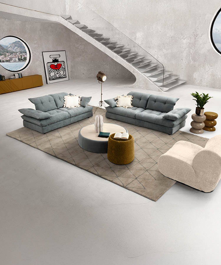 Un salon moderne avec deux canap s gris, un lampadaire sur tr pied, une plante en pot et un escalier flottant en b ton avec une rampe en verre contre un mur blanc textur . Description g n r e par IA