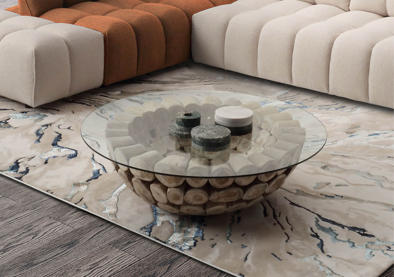 Table basse ronde avec plateau en verre transparent et base remplie de morceaux de bois, entour e de canap s rembourr s beige et marron sur un tapis clair  motifs abstraits.  Description g n r e par IA