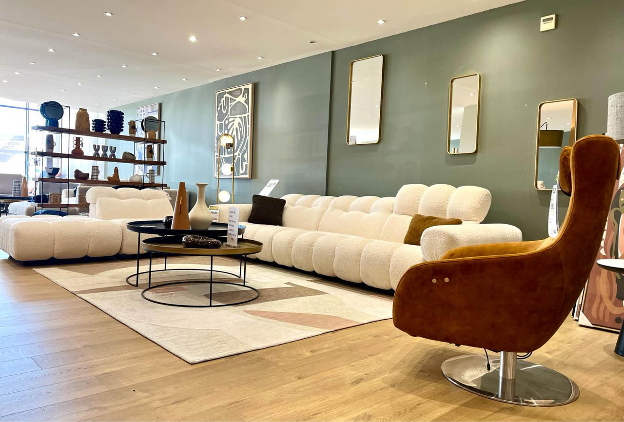 Un salon moderne avec un canap blanc modulable, une chaise en velours marron, une table basse ronde et des  tag res d coratives contre un mur vert.  Description g n r e par IA